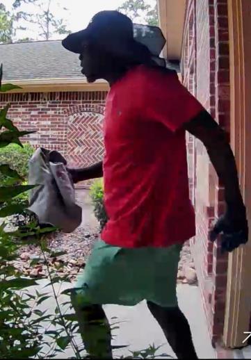 Photo of suspect carrying something in his right hand, leaving the home. Suspect was wearing a wide brimmed had, red shirt and green shorts. 